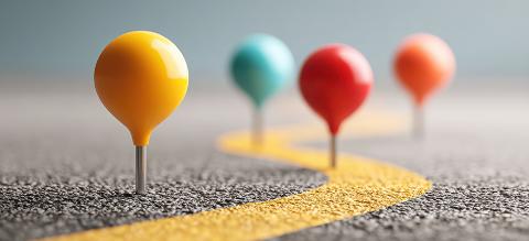 A row of colorful pins placed along a road representing strategic planning and milestones in project development journey