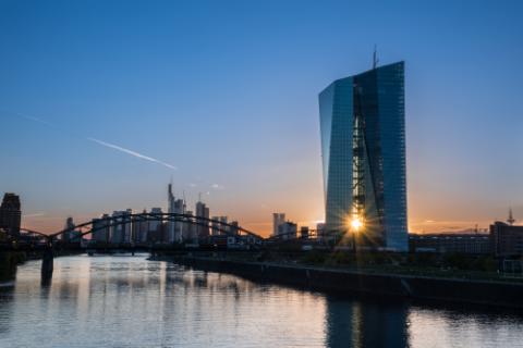 Frankfurt am Main, Germany -May 13th 2019. .European Central Bank (ECB) Tower  and Skyline with a orange-blue Sunsetreflected on the water of the Main River. The sun shines through the ECB towers