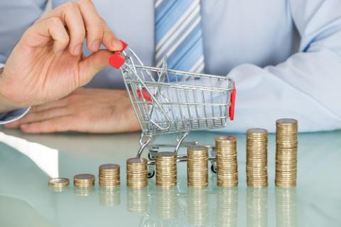 Businessman With Stacked Coins And Small Shopping Cart