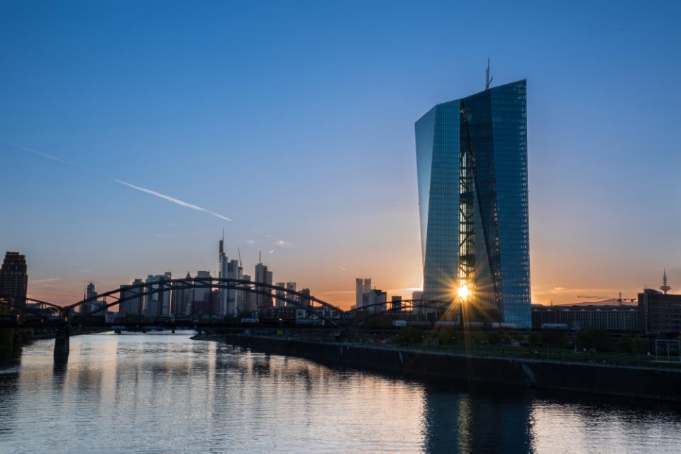 Frankfurt am Main, Germany -May 13th 2019. .European Central Bank (ECB) Tower  and Skyline with a orange-blue Sunsetreflected on the water of the Main River. The sun shines through the ECB towers
