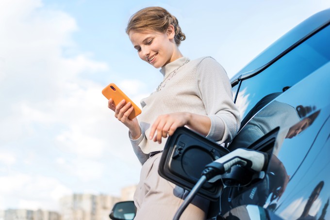 Young woman with an electric car at charging station in Chisinau, Moldova