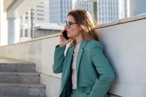 Business woman standing on stairs outside office building while talking on cellphone 