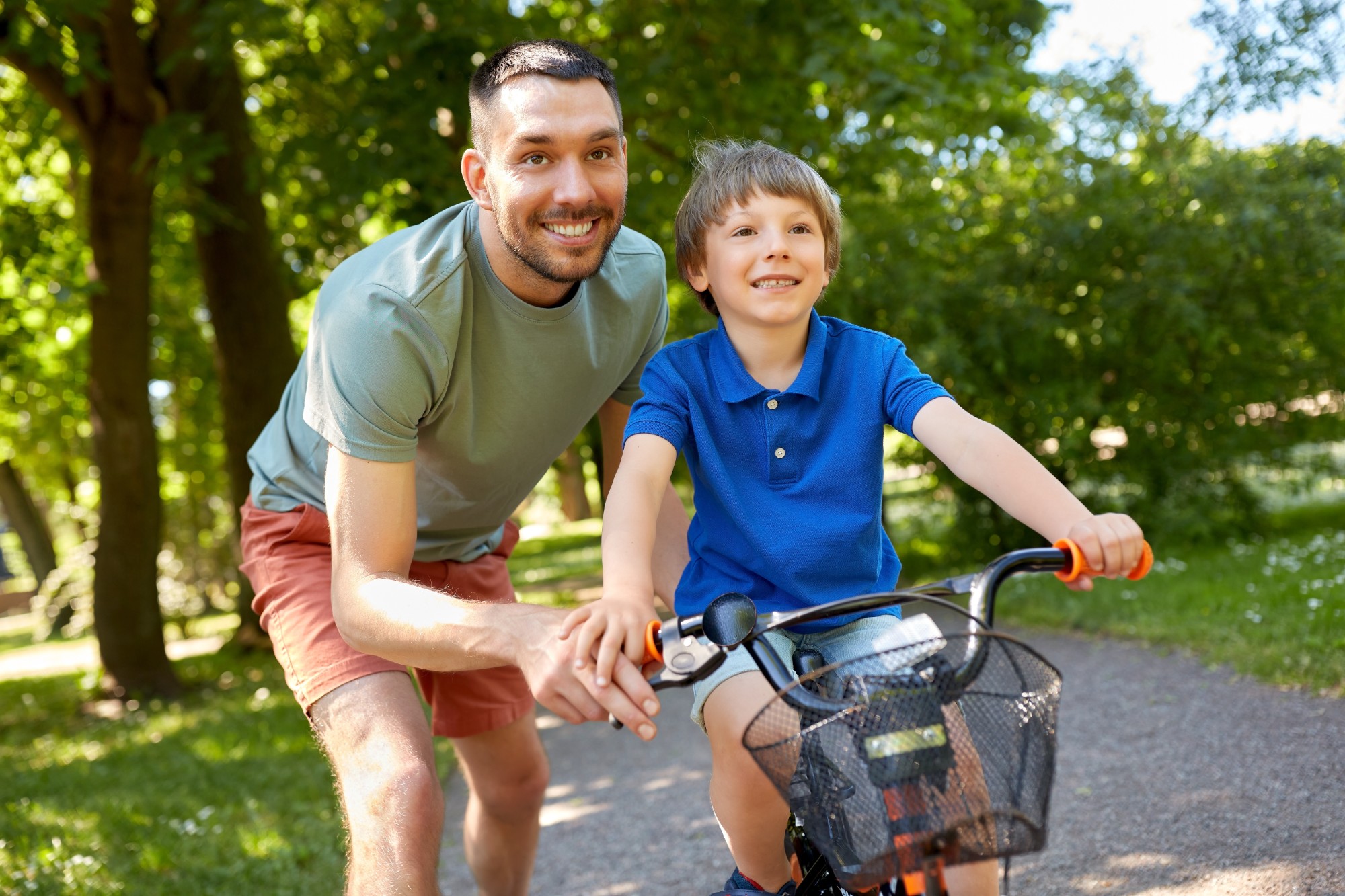 father teaching little son to ride bicycle at park