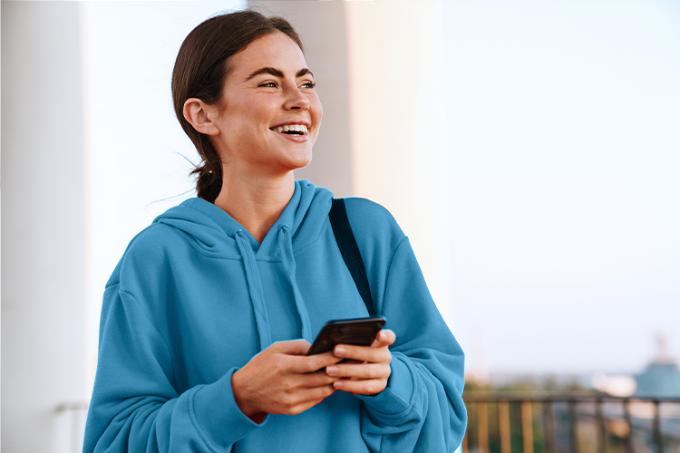 vrouw met smartphone vraagt persoonlijke lening aan - illustratieve afbeelding