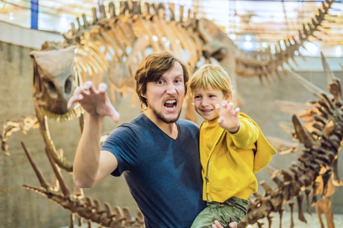 Vader en zoon staan voor dinosaurus in museum