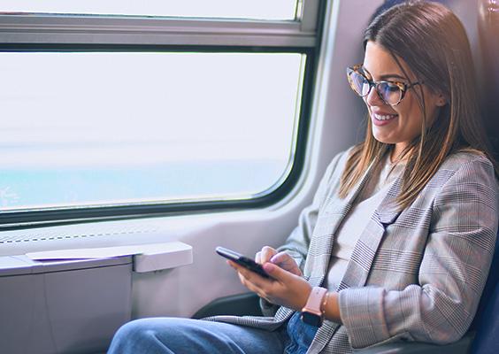NMBS nieuwe tarieven vrouw kijkt op haar smartphone in de trein