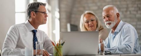 Bank manager and senior couple using laptop on a meeting in the office. 