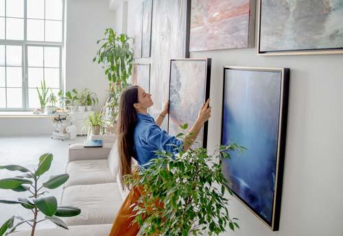Vrouw hangt schilderij op in galerij Vrouw hangt schilderij op in galerij